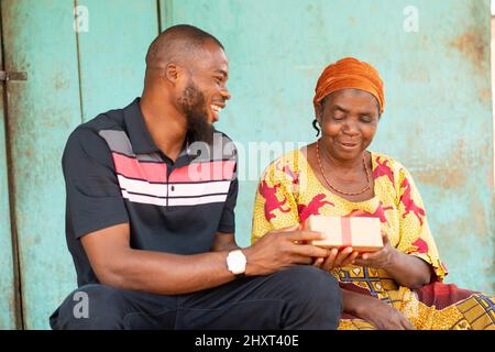 Jeune homme noir donnant un cadeau à sa mère plus âgée Banque D'Images