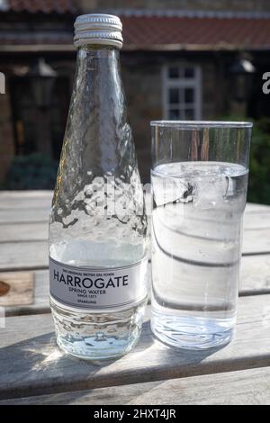 Harrogate Spa eau minérale pétillante, l'eau de source British Spa Town depuis 1571 bouteille et verre sur une table extérieure Banque D'Images