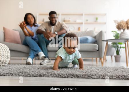 Un bébé mignon qui marche dans le salon fait les premiers pas Banque D'Images