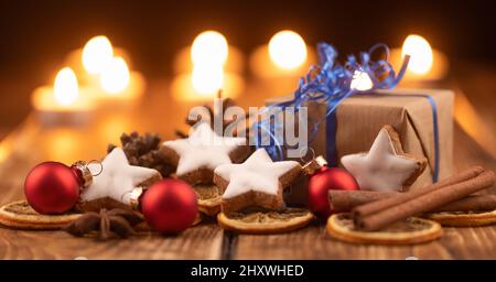 Un cadeau avec quelques biscuits en forme d'étoile sur le sol à l'arrière-plan de bougies. Banque D'Images