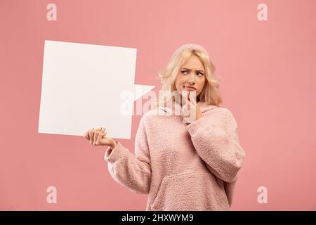 Jeune femme pensive touchant le menton, tenant et regardant la bulle de parole vide avec espace vide pour votre texte ou de conception Banque D'Images