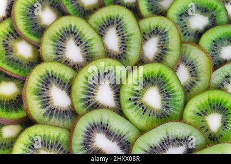 Fond en tranches de kiwi. Morceaux de fruits mûrs et frais. Gros plan de tranches de kiwi. Banque D'Images