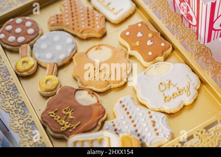 Biscuits de différentes formes avec le mot « Oh bébé » en or sur certains d'entre eux dans un plateau doré Banque D'Images