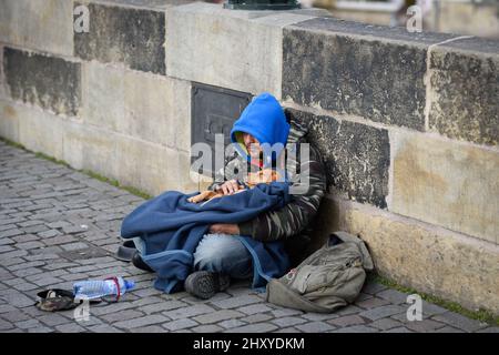 Un sans-abri assis avec un chien dans la rue à Prague, en République tchèque Banque D'Images