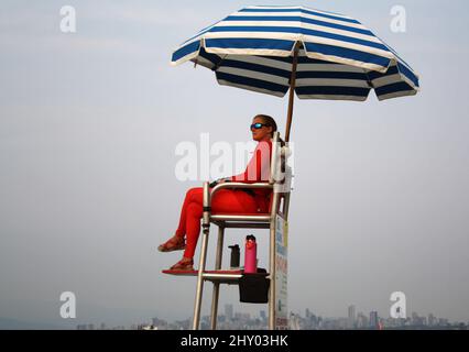 Maître nageur assis sous un parapluie à Kitsilano Beach, Vancouver, Canada Banque D'Images