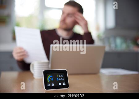 Compteur d'énergie intelligent dans la cuisine mesure de l'utilisation de l'électricité et du gaz avec l'homme regardant des factures Banque D'Images