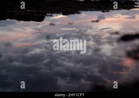 Grand angle de ciel nuageux avec coucher de soleil réfléchissant sur la flaque sur la rive de l'île de Ténérife Banque D'Images