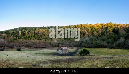 Prairie verte avec maison simple située contre des bois verdoyants sous ciel bleu sans nuages en plein jour en Espagne Banque D'Images