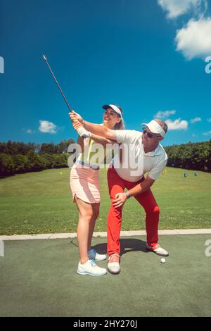 Golf professionnel enseignant une femme étudiant de l'aire d'échauffement Banque D'Images