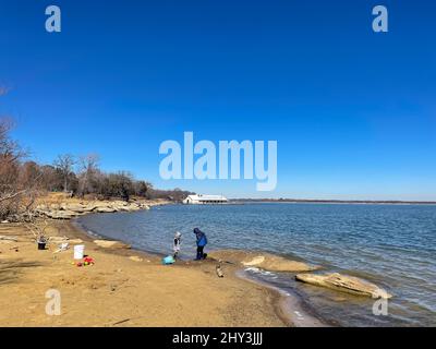 Vue lointaine des enfants jouant sur la rive sablonneuse du lac Lewisville au Texas, aux États-Unis Banque D'Images