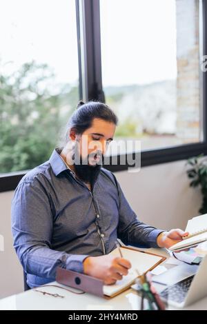 jeune homme travaillant à la maison comme indépendant préparant un projet important Banque D'Images