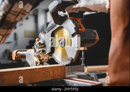 Menuisier à l'aide d'une scie circulaire électrique, coupant un morceau de bois. Photo de haute qualité. Banque D'Images