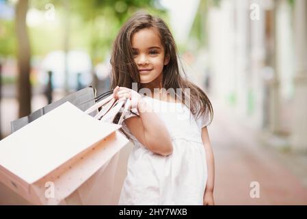 Oubliez les heures de jeu - je veux faire mes achats toute la journée. Portrait d'une adorable petite fille tenant des sacs de shopping dans la ville. Banque D'Images