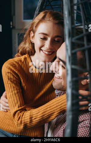 Vue rapprochée d'un couple à la maison assis sur un canapé pour passer un week-end ensemble. Visages caucasiens souriants. Banque D'Images
