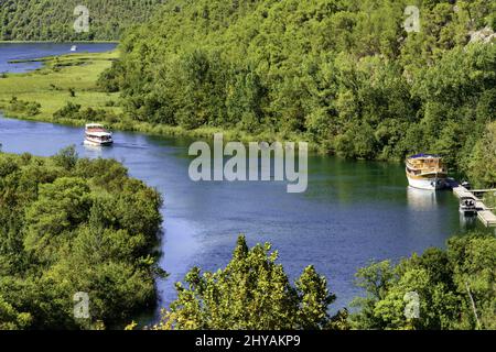 Photo aérienne d'une rivière calme et sinueuse avec des bateaux qui traversent une forêt dans le parc national de Krka Banque D'Images