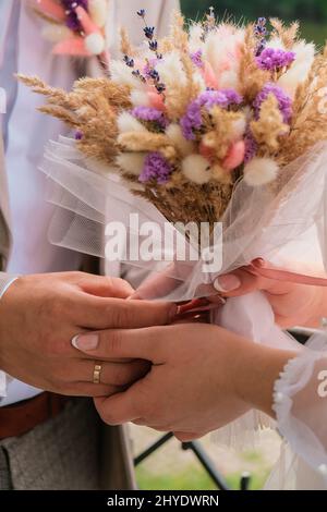 Le bruit de fond des fleurs dans les mains.Mariée tenant son bouquet de désherbage de fleurs sèches.Bouquet fait main.Désherbage de décorations Banque D'Images