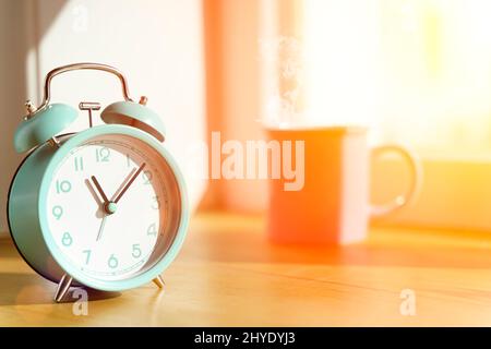 Réveil le matin sur la table dans la chambre à coucher contre le fond de la fenêtre avec le soleil du matin. Réveil, heure, nouveau jour, concept d'optimisme. Photo de haute qualité Banque D'Images