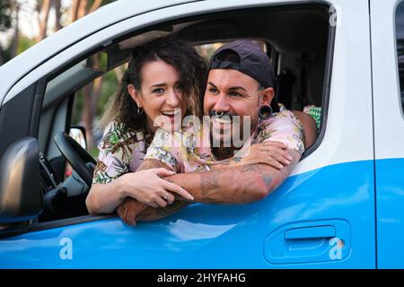 Un jeune couple tatoué riait en collant sa tête hors de la fenêtre de la camionnette. Banque D'Images