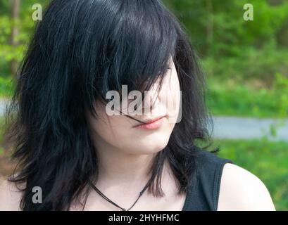 Femme gothique emo avec cheveux noirs et vêtements noirs, regardant loin, gros plan Banque D'Images