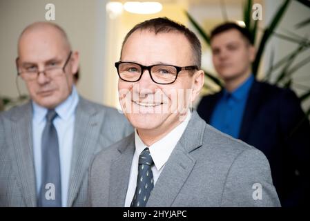 Portrait d'un homme d'affaires souriant et confiant debout avec des membres de l'équipe en arrière-plan Banque D'Images