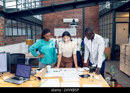 Jeunes architectes multiraciaux, hommes et femmes, travaillant sur Blueprint au bureau Banque D'Images