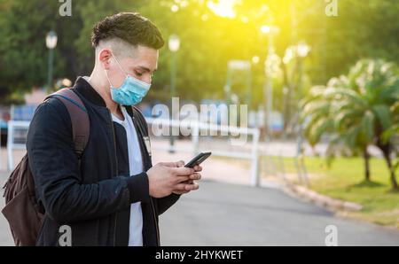 Un homme beau qui envoie des SMS avec son téléphone, un jeune homme beau qui se trouve dans un masque facial envoie des SMS avec son téléphone, un homme beau qui envoie des SMS sur son téléphone Banque D'Images