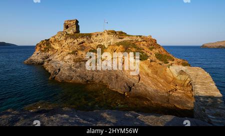 Super grand angle, forteresse en ruines sur l'île rocheuse au large, lumière douce du soir, drapeau national grec, bleu foncé de mer, bleu ciel et sans nuages, Andros Banque D'Images