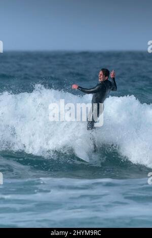 Un surfeur qui profite de l'hiver en surfant à Fistral à Newquay, en Cornouailles, au Royaume-Uni. Banque D'Images