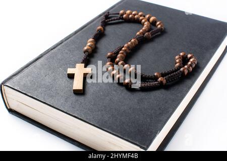 Croix catholique Rosaire sur la Sainte Bible isolée sur fond blanc Banque D'Images