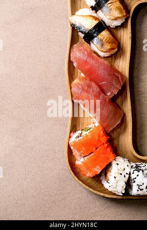 Ensemble de petits pains à sushis. Sushi traditionnel japonais et petits pains avec saumon frais, thon, anguille et crevettes sur le riz. Servir sur une assiette en bois avec des baguettes Banque D'Images
