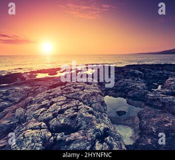 Un incroyable soleil rouge sur la mer. Île volcanique de Malte. Qawra, Europe. Le monde de la beauté. Effet rétro-tonant. Banque D'Images
