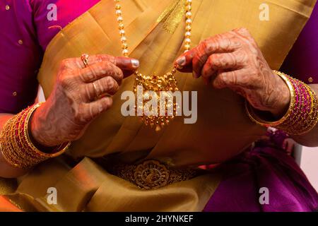 Gros plan des mains de la mariée indienne touchant son collier d'or Banque D'Images