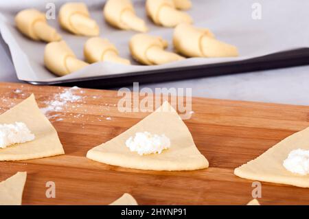 Préparation de l'essai pour les croissants. La pâte est coupé en tranches dans un triangle. Banque D'Images