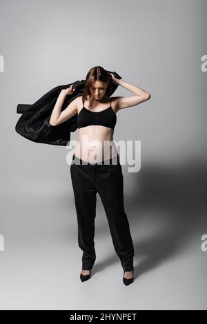 Femme enceinte tendance portant un blazer sur fond gris Banque D'Images