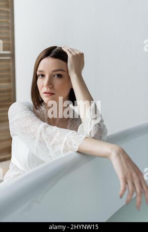 Brunette femme en robe posé près de la baignoire à la maison Banque D'Images