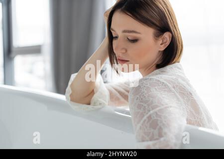 Femme en robe de dentelle regardant le peignoir à la maison Banque D'Images