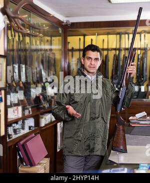 Homme moderne hunter choisir en magasin avec fusil de chasse équipement Banque D'Images