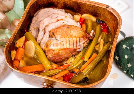 Steak de porc émincé sur une pile de légumes dans une poêle rustique en faïence, un porte-jarretelles, un gros plan. Banque D'Images