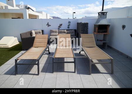 trois chaises longues, un canapé et un barbecue dans le jardin d'une villa playa blanca lanzarote, îles canaries, espagne Banque D'Images