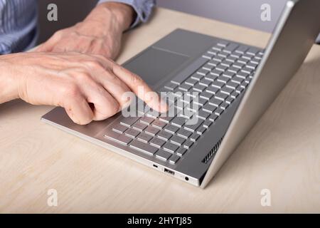 Homme main fermer à l'aide de l'ordinateur portable et en appuyant sur la touche entrée. Saisie de messages, recherche d'informations, réalisation de projets, utilisation de l'ordinateur pour le travail et le concept d'éducation. Photo de haute qualité Banque D'Images