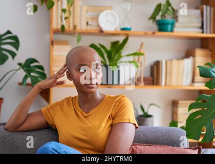 Une jeune femme se détend sur son canapé devant une étagère avec des plantes Banque D'Images