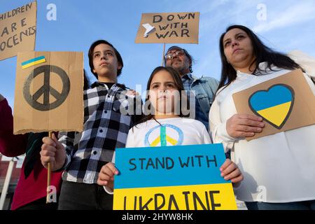 Un groupe de manifestants pour la paix proteste contre l'invasion russe. Ils présentent des affiches et des drapeaux de la fin de la guerre aux couleurs ukrainiennes. Banque D'Images