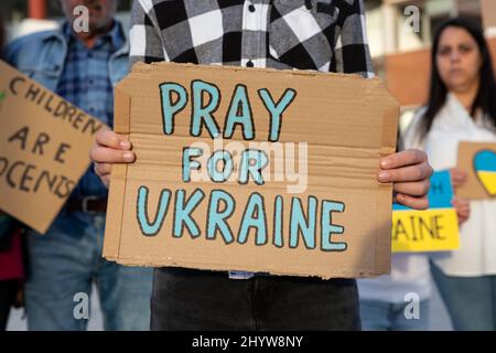 Un démonstrateur de garçon présente un panneau en carton pour soutenir le peuple ukrainien lors d'une manifestation de rue anti-guerre. Banque D'Images