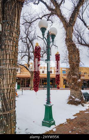 De longs rivestras au poivre rouge lacés de neige un matin d'hiver sur la place historique de Santa Fe, Nouveau-Mexique Banque D'Images