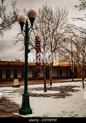 De longs rivestras au poivre rouge lacés de neige un matin d'hiver sur la place historique de Santa Fe, Nouveau-Mexique Banque D'Images