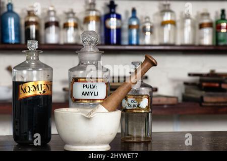 Des rangées de bouteilles en verre derrière un bol de mélange et un pilon dans une pharmacie victorienne, faisant partie de l'organisme de bienfaisance Holly Lodge Centre à Richmond Park, Surrey Banque D'Images