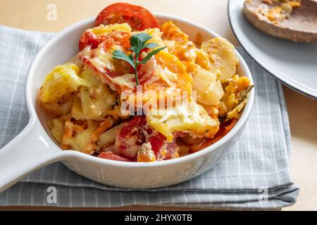 Cocotte avec pomme de terre, patate douce, tomate et fromage. Banque D'Images