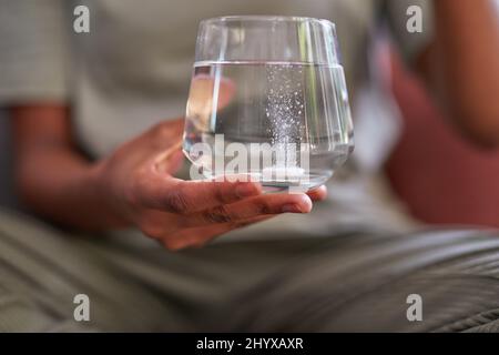 Un gros plan d'un comprimé effervescent fuzzy dans un verre d'eau pour le traitement de la grippe Banque D'Images