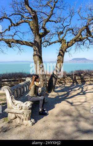 Beau lac balaton paysage à Fonyod Hongrie avec banc de pierre décoré et la colline de badacsony sur le fond avec la femme touristique Banque D'Images