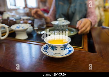 Tasse à thé en porcelaine avec de beaux motifs bleus. Rempli de thé pu Erh, style gung fu cha. Arrière-plan flou. Janvier 2020. Banque D'Images